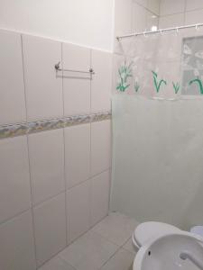 y baño blanco con ducha y aseo. en Apartamento / Kitnetes, en Peruíbe