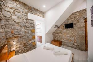 a bedroom with a stone wall and a bed at Hortensia House in Cefalù