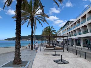 a beach with palm trees and a building at Santiago Oceanfront Living in Sesimbra