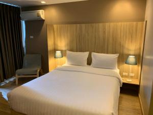 Un dormitorio con una gran cama blanca y una silla. en Baan Tanwa - MRT Ratchadapisek Exit 1 or 2, en Bangkok