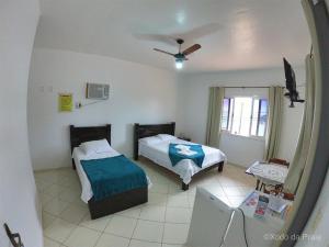 a bedroom with two beds and a ceiling fan at Pousada Xodó da Praia in São Pedro da Aldeia