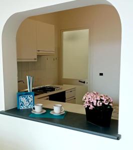 a kitchen with two cups and a table with flowers at Georgia House in Torre Suda
