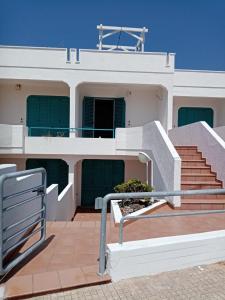 a white building with green doors and stairs at Georgia House in Torre Suda