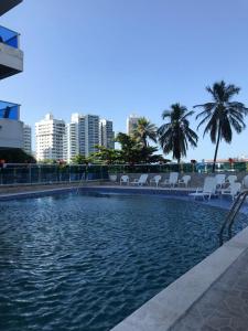a swimming pool with chairs and palm trees in a city at Ocean blue Ed Conquistador in Cartagena de Indias