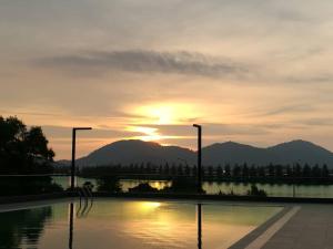 a sunset over a pool of water with mountains in the background at Marina Heights Resort in Lumut
