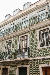リスボンにあるロシオ コンヴェント ダ エンカルナサンの窓とバルコニー付きの緑と白の建物