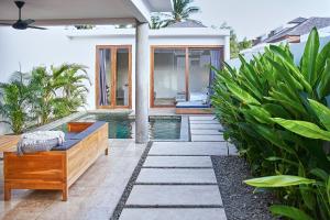 un patio trasero con piscina y una casa en Kumbara Villas en Kuta Lombok