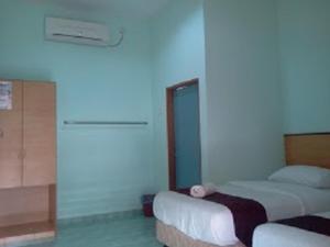 a bedroom with two beds and a blue wall at Rose Inn Motel in Kuah