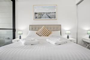 a bedroom with a white bed with two towels on it at Rockpool 2 Sawtell Beach - Just steps to Restaurants and 2 min Stroll to Beach! in Sawtell