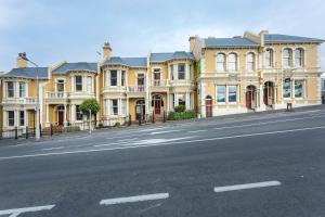un gran edificio amarillo en el lateral de una calle en The Stuart Street Terraced House, en Dunedin