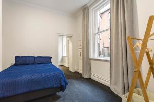 um quarto com uma cama azul e uma janela em The Stuart Street Terraced House em Dunedin