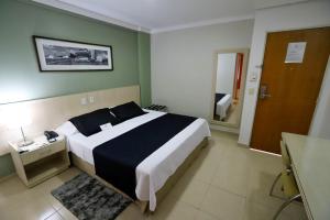a hotel room with a bed and a desk at Hotel Maione in Goiânia