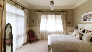 a bedroom with a bed and a chair and a window at The Willows at Kurrajong in Kurrajong