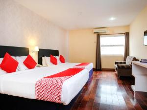 a hotel room with a large bed with red pillows at Super OYO 546 Grand City Hotel in Kuantan