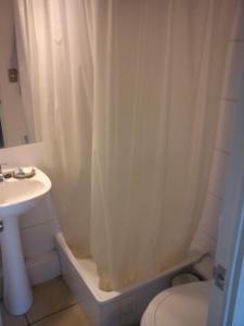 a bathroom with a white shower curtain and a sink at Frente al parque (Solo mujeres) in Santiago