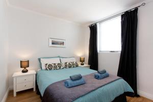 a bedroom with a bed with two blue pillows on it at Ocean Breeze Apartment in Fremantle