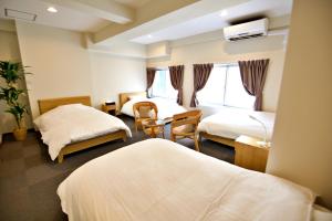 泉佐野市にあるKURA HOTEL IZUMISANOのベッド2台とデスクが備わるホテルルームです。