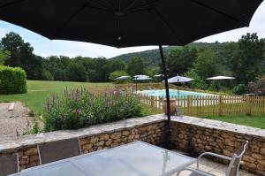 a table with an umbrella next to a pool at gîtes les 7 roches 6 couchages in Les Eyzies-de-Tayac