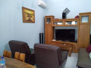 ein Wohnzimmer mit einem TV, einem Tisch und Stühlen in der Unterkunft KJ Blue House Senggigi in Senggigi 