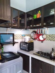 eine Küche mit einer Mikrowelle, einem Herd und Schränken in der Unterkunft KJ Blue House Senggigi in Senggigi 