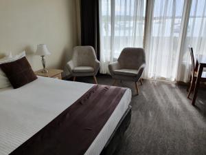 a hotel room with two beds and a chair at Waters Edge Port Macquarie in Port Macquarie