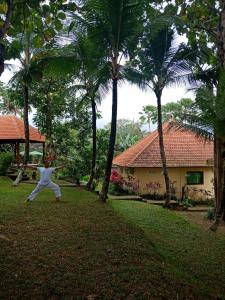 a man is standing in a yard with palm trees at Argasoka Bungalows in Ubud