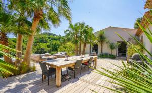a wooden table and chairs on a deck with palm trees at villa Sant-Anna in Saint-Tropez