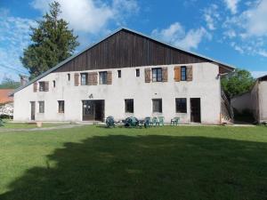 un grand bâtiment blanc avec des tables et des chaises dans une cour dans l'établissement Auberge Le Sillet, à Longcochon