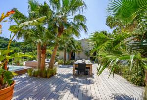 a wooden deck with a table and palm trees at villa Sant-Anna in Saint-Tropez
