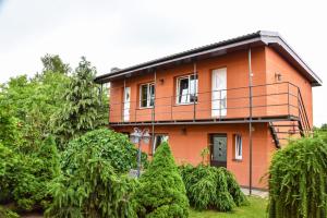 a orange house with a balcony on top of trees at Zelta pirts Guest House in Ventspils