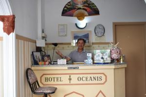 ティロスにあるOceanis Hotelのホテルの部屋のカウンターに座る男