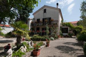 a house with flowers and plants in front of it at Apartments Nadia Sokolić in Nerezine