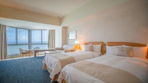 une chambre d'hôtel avec deux lits et un salon dans l'établissement Grandvrio Resort Saipan, à Garapan