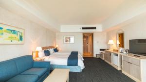 a hotel room with a bed and a blue couch at Grandvrio Resort Saipan in Garapan