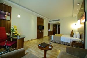 a hotel room with a bed and a living room at Gokulam Park Coimbatore in Coimbatore