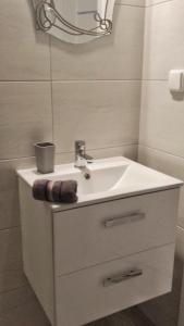 a white bathroom with a sink and a mirror at Apartament Baltic in Sztutowo