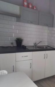 uma cozinha com armários brancos e um lavatório em Apartament Baltic em Sztutowo