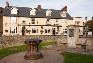 een bankje voor een groot gebouw bij Anchor Inn by Greene King Inns in Beer