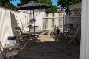 eine Terrasse mit einem Tisch, Stühlen und einem Sonnenschirm in der Unterkunft Guest House Tullgatan 24 in Borgholm