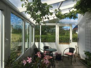 einen Wintergarten mit Stühlen, Tischen und Fenstern in der Unterkunft Margretelyst in Farsø