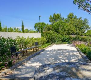 a park with two benches and trees and bushes at villa Sant-Anna in Saint-Tropez