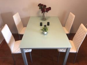 una mesa blanca con sillas y un jarrón de flores. en Estival Park, en La Pineda