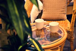 two coffee mugs sitting on a wicker chair at KURA HOTEL IZUMISANO in Izumi-Sano