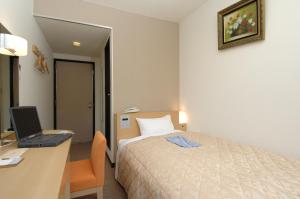 Hamada New Castle Hotel في Hamada: غرفة في الفندق مع سرير ومكتب مع لاب توب