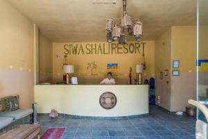 une femme se tenant derrière le comptoir d'un salon dans l'établissement Siwa Shali Resort, à Siwa