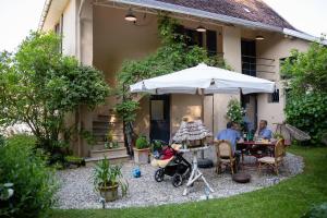 a group of people sitting at a table under an umbrella at Côté Jardin, Chambres d’hôtes B&B in Le Pont-de-Beauvoisin