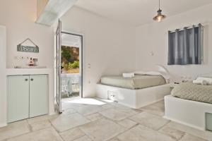 ein weißes Schlafzimmer mit einem Bett und einem Spiegel in der Unterkunft Villa Stamatina in Kyra Panagia