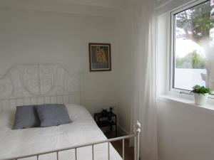 Habitación blanca con cama y ventana en White Willows, en Praa Sands