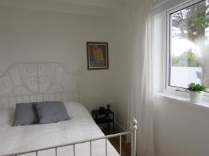 a white bedroom with a bed and a window at White Willows in Praa Sands
