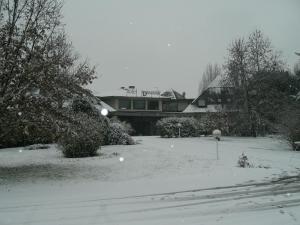 une cour recouverte de neige avec une maison en arrière-plan dans l'établissement Hotel I Diamanti, à Garlasco